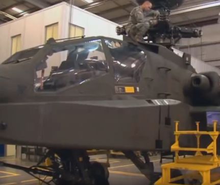 Soldier working on Apache helicopter in hangar